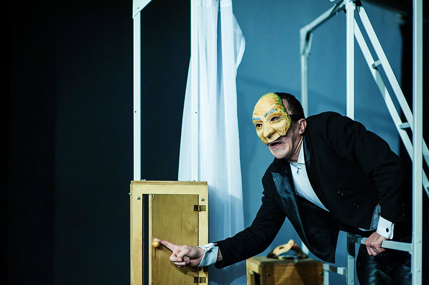 Zdjęcie ze spektaklu Pan Kot. Przedsawia aktora w e fraku, bez koszuli z maską w stylu komedii de larte na twarzy.