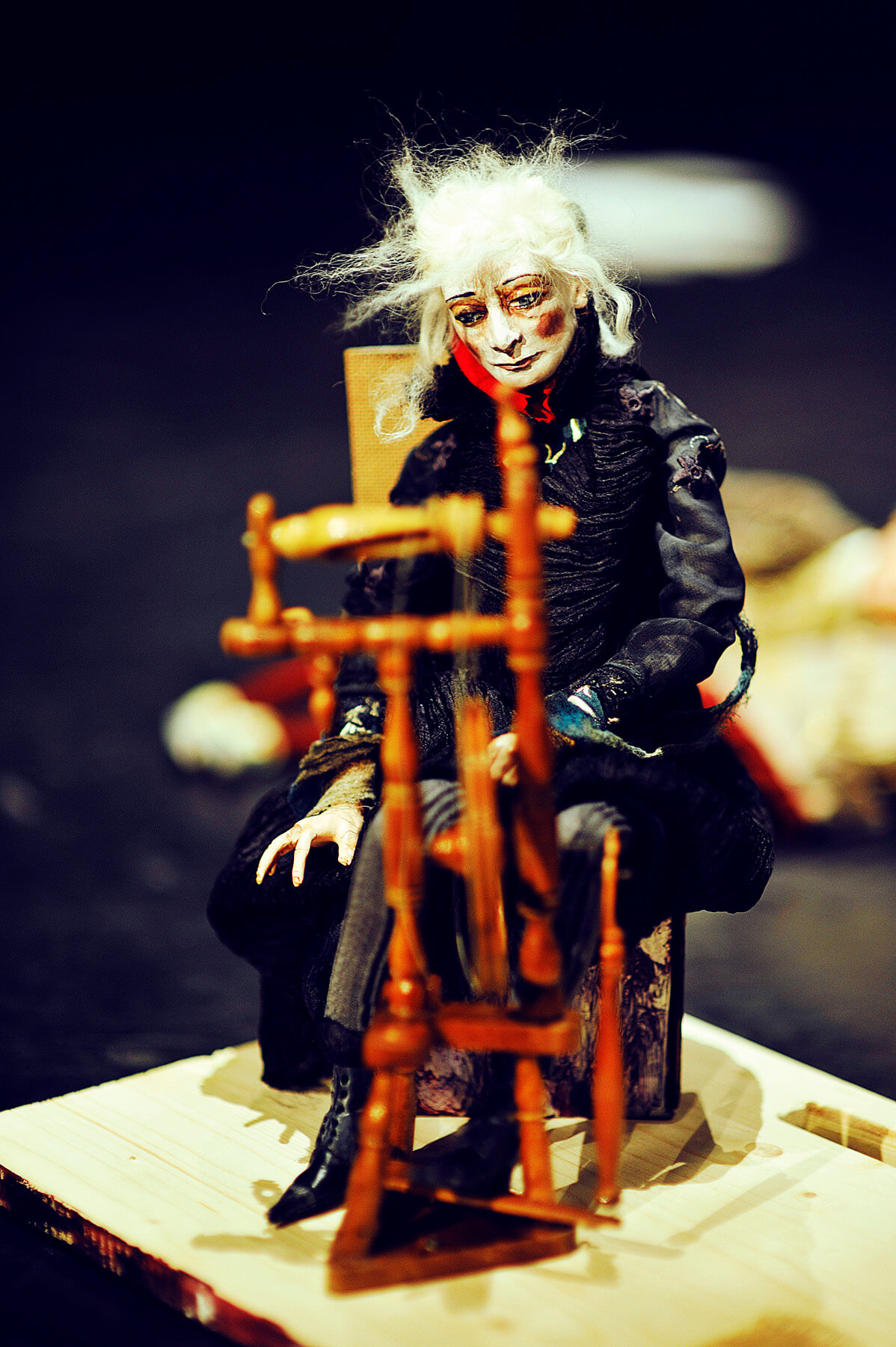 Zdjęcie do spektaklu spiąca Królewna. Pokazuje lalkę czarownicy siedzącą przy kołowrotku.