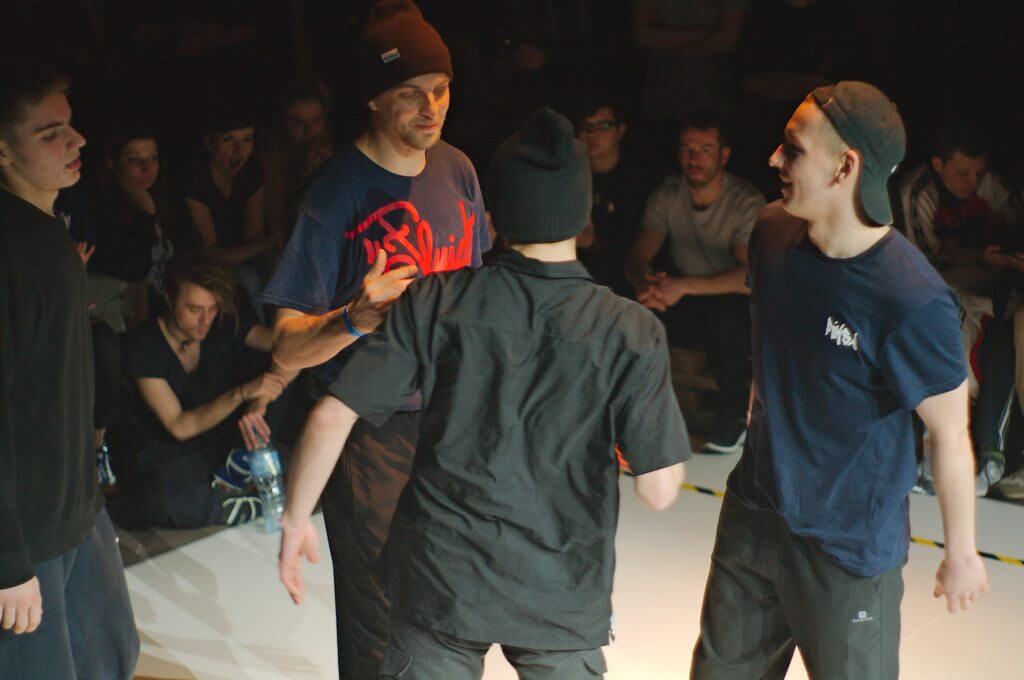 Zdjęcie z zawodów Gdynia Breaks. Na scenie stoi czterech mężczyzn, którzy wspólnie sobie gratulują i podają ręce.