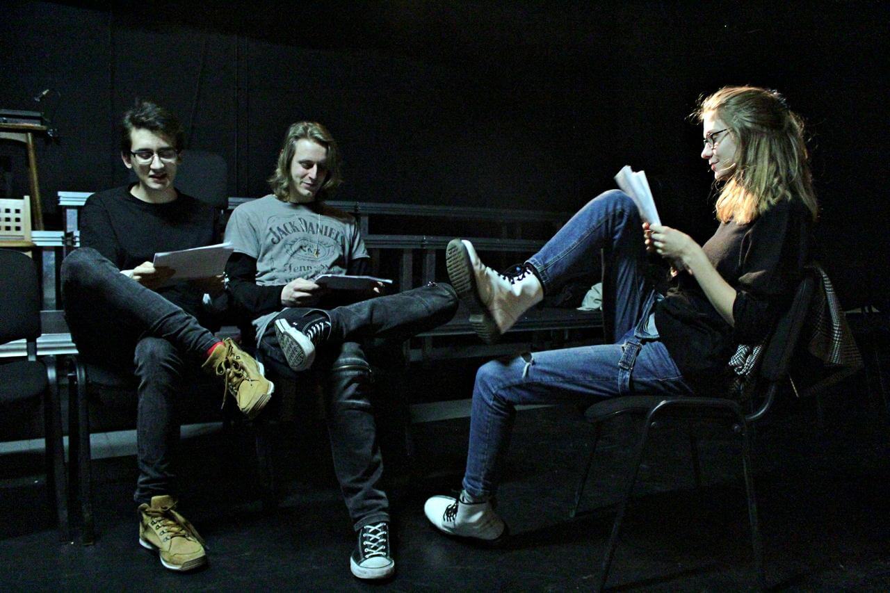 Zdjęcie z projektu Teatr Młodych. Trzech uczestników. Dwóch mężczyzn siedzi na przeciwko kobiety i wspólnie zapoznają się ze scenariuszem.