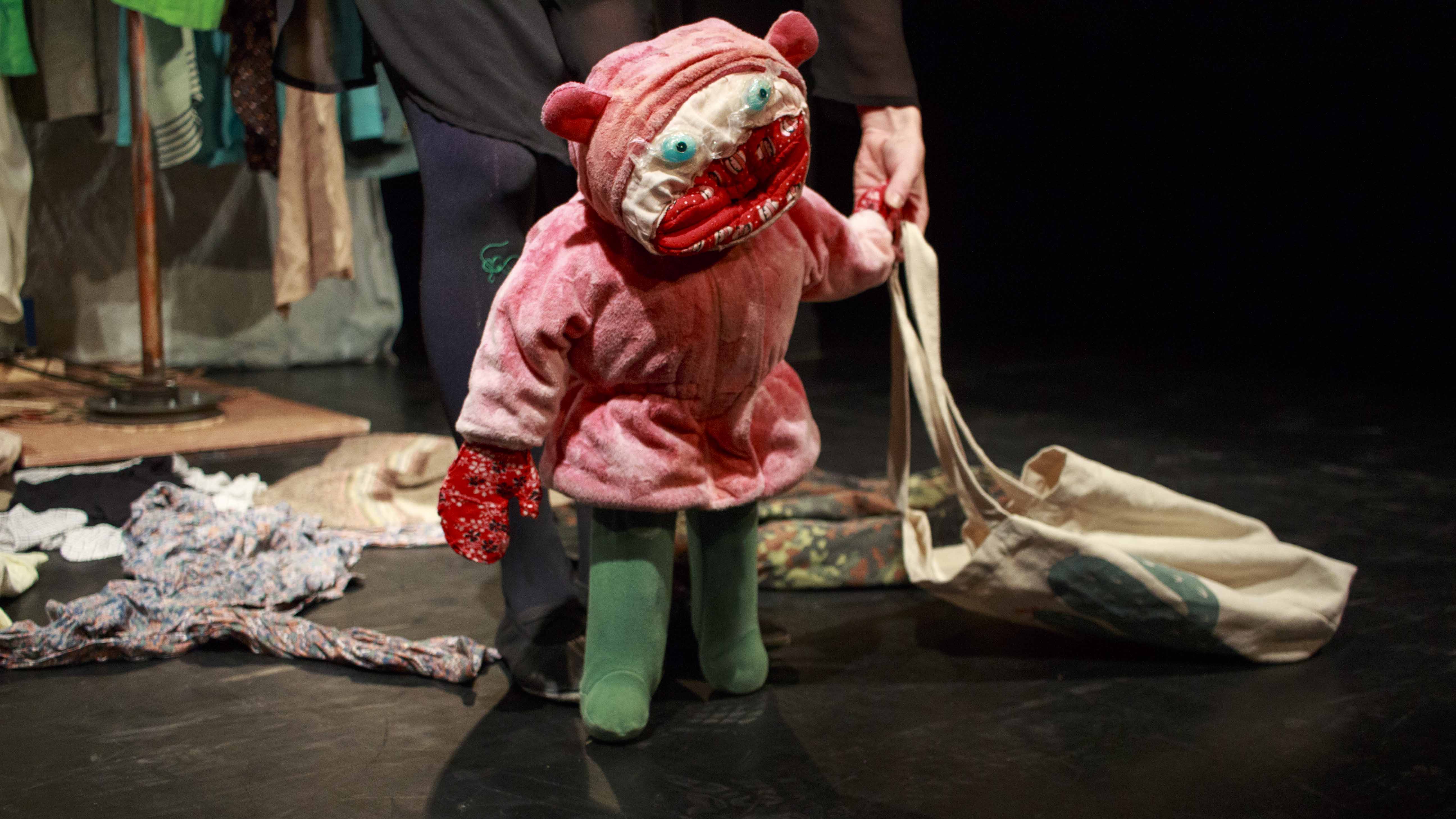 Zdjęcie do spektaklu Czerwony Kapturek (trochę inna historia). Aktorka trzymająca kukiełkę czerwonego kapturka. Kukiełka ma przymocowaną do dłoni siatkę na zakupy.