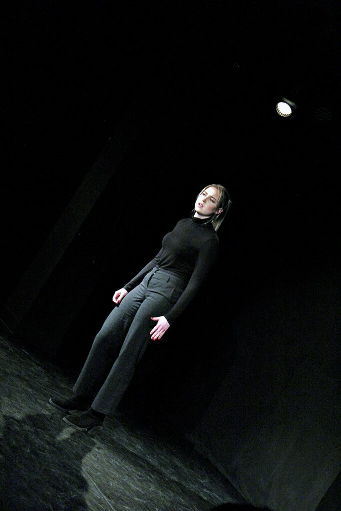na scenie stoi kobieta ubrana na czarno, jest w trakcie mówienia, włosy ma spięte w kucyk, zdjęcie z wydarzenia teatru gdynia główna