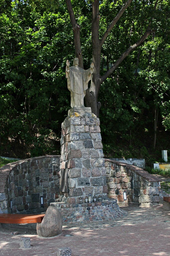 pomnik ukazujący jezusa o rozpostartych rękach znajdujący się w gdyni orłowie, w tle drzewa