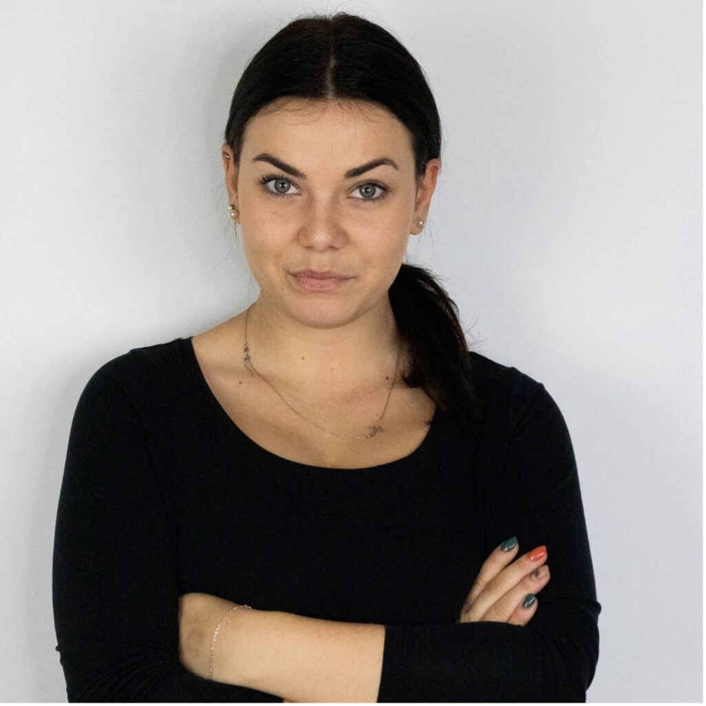 Zdjęcie portretowe, kobieta ubrana na czarno, na białym tle, ręce skrzyżowane przed sobą