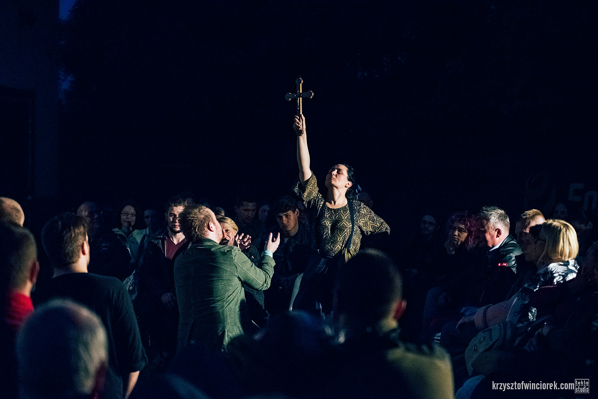 Zdjęcie z festiwalu Pociąg do miasta. Pośrodku tłumu aktorka podnosi rękę w której trzyma krzyż.