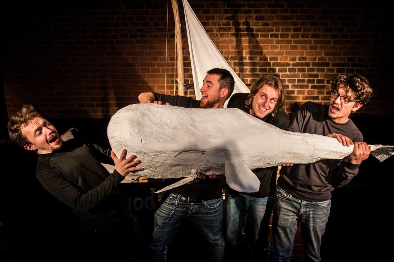Zdjęcie do spektaklu Dzielny Kapitan Ahab. Czterech aktorów trzyma przed soba lalkę białego wieloryba.